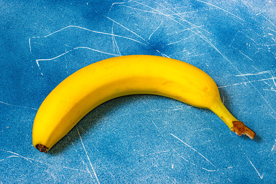 Closeup of a ripe yellow banana on a blue textured background