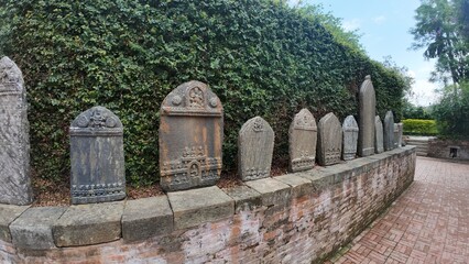 Ancient Stone Memorial Tablets Lined Along Brick Wall in Peaceful Garden Pathway in Nepal