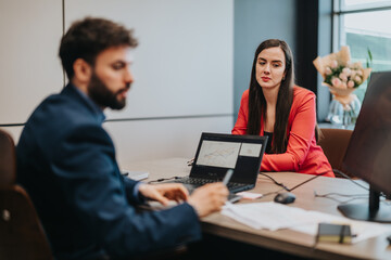 Business people collaborating in a modern office, discussing data visually displayed on a laptop.