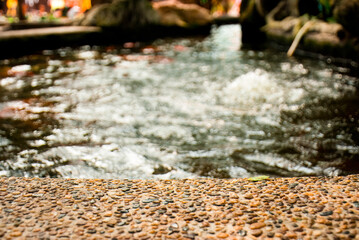 Beautiful pebble pond edge behind a water feature, Pebble stone koi pond edge for product display.