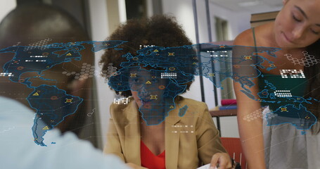Image of world map over diverse business people in office