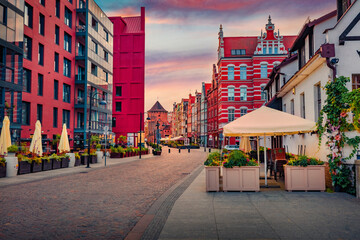 Red modern and old buildings on the empty street of Gdansk. Colorful morning cityscape of Gdansk. Fantastic summer sunrise in old port on Baltic sea, Poland, Europe. Traveling concept background..