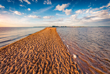 Wonderful summer sunrise on Baltic sea with the end of the sand spit with a lots of footsteps. Amazing endless clouds  in blue sky. Picturesque morning scene of Rewa public beach, Poland, Europe.