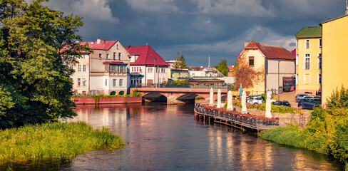Panoramic summer view of colorful buildings on the shore of Wieprza river. Sunny morning cityscape of  Darlowo town, Poland, Europe. Traveling concept background.
