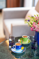 A welcome gesture at a hotel, Turkish coffee for two with chocolate and water on a marble tabletop in a hotel room setting with soft window light