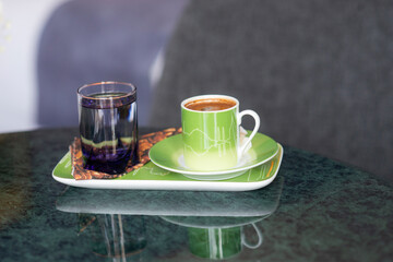 A welcome gesture at a hotel, Turkish coffee with Turkish delight sweets and water on a marble tabletop in a hotel room setting with soft window light