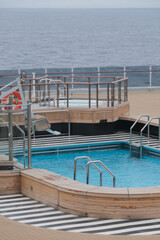 Outdoor whirlpool jacuzzi and private sun deck onboard modern luxury cruiseship cruise ship ocean liner with turquoise water, elegant rattan loungers and deck chairs for suite guests passengers