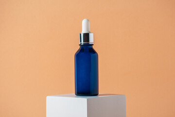 Blue glass cosmetic bottle, Skin care or sunscreen cosmetic with stylish props on cream background.