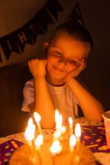 little boy makes wishes and blows out candles on a birthday cake