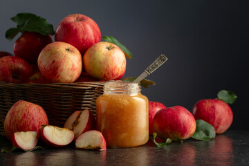 Apple jam and fresh apples on a black stone table.