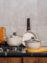 There are white pots and pans placed on a stove top in a kitchen