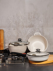 A collection of white pots and pans featuring glass lids resting on a stove top