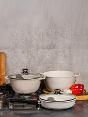There are three white pots and pans placed neatly on a stove top