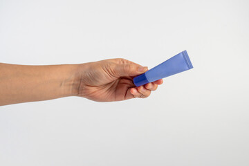 Obraz premium Purple packaging for cream, sunscreen or serum in hand on white background.