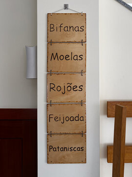 Camino de Santiago trail sign with a yellow scallop shell icon and directional arrow on a white concrete wall.