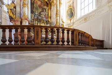 Interior of historical church featuring ornate altar and polished wooden railing in the afternoon...