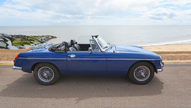 Classic  Blue MG MGB roadster parked on seafront Promenade beach and sea in background