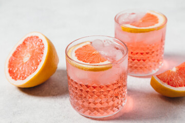 A refreshing negroni rosa cocktail served in a textured glass with ice, garnished with a slice of...
