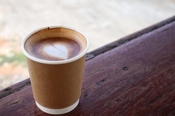 Coffee latte art milk foam on cup on wood background
