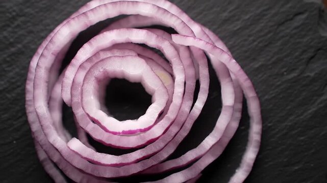 Circular Slices Of Red Onion on Black Slate Plate