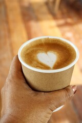 Coffee latte art milk foam and cup on hand