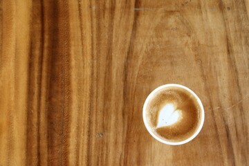 Coffee latte art milk foam on cup on wood background