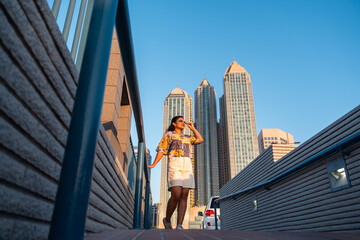 Fototapeta premium young woman traveler exploring Abu Dhabi corniche with Highrise buildings background 