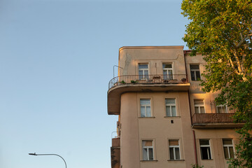This delightful view showcases a stunning residential building with elegant balconies that enhance its charm against a sunny blue sky, creating a picturesque sight for all to admire