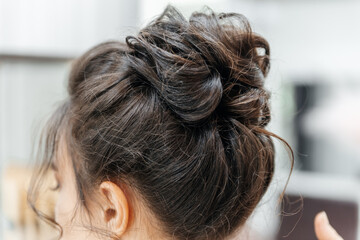 Woman with a bun on her head. She is getting her hair done
