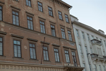 The image features two distinct building facades with various architectural styles, highlighting elaborate windows and intricate details that enhance the urban cityscape