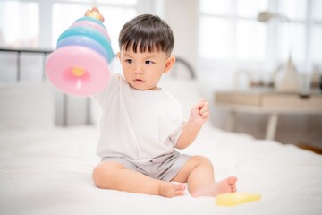 Fototapeta premium Young child playing with colorful stacking rings indoors during daytime in a bright room