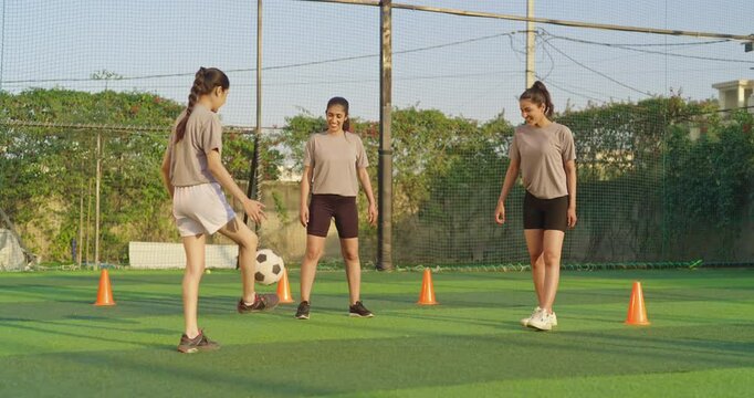 Indian happy young adult gen z group sports woman playing football together at outdoor playground yard smiling female players practice game kicking soccer ball enjoying team outside ground place - Powered by Adobe