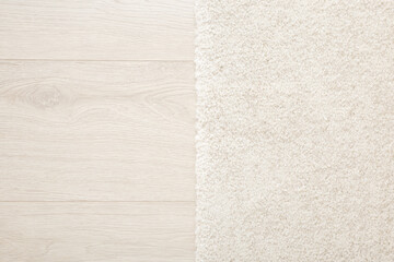 White new fluffy home carpet on light color laminate background. Closeup. Two sides. Top down view.