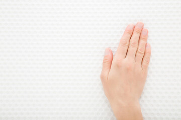 Young adult woman hand touching clean white orthopedic mattress or pillow new cloth material. Checking hardness and softness. Closeup. Top down view.