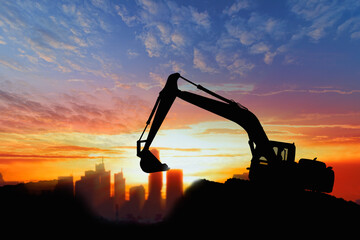 Crawler excavators silhouette are digging the soil in the construction site. With sky and clouds of on sunset background
