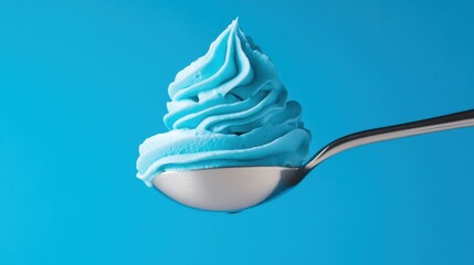 Close-up of swirled blue whipped cream on a spoon floating against a vibrant sky-blue background