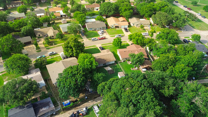 Middle-class single-family houses in Cockrell Hill neighborhood, South Dallas, Texas, established residential area lush greenery, tree lined street, overhead power lines near Mountain View Park