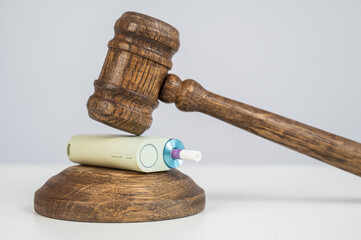 Judge's gavel hits e-cigarette. Smoking ban. Tobacco heating systems. 