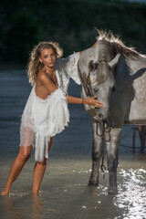 Beautiful and sensual woman with long hair ,white bikini and white blouse rides  on a white horse...