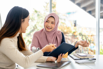 Business meeting with diverse professionals. Two women discussing work, taking notes. Professional attire, diverse team, collaborative environment. Diverse people business corporate meeting.