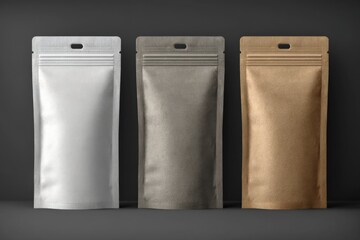 Three sealed packaging bags in silver, gray, and brown colors displayed against a dark background