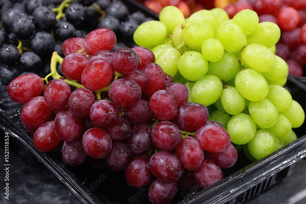 Poster fresh grapes in various colors displayed in a market for customers to select during a sunny afternoo