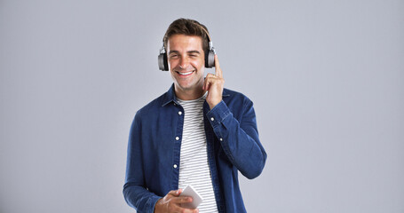 Headphones, happy and man with phone in studio listening to music, playlist or album on mobile app....