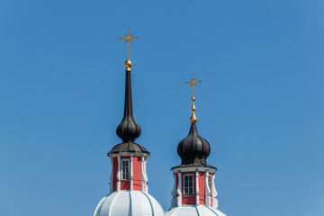Two church towers with black domes and golden crosses of the cathedral against a blue sky background.