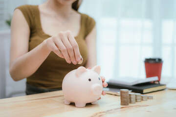 Woman putting money in piggy bank, money saving concept
