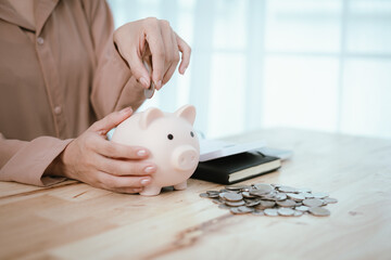 Woman putting money in piggy bank, money saving concept
