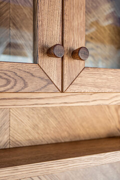Beautifully crafted oak timber cabinet with glass fronts and intricately designed wooden knobs close view