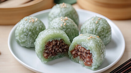 Green qingtuan glutinous rice balls with Chinese mugwort and barley on plate.