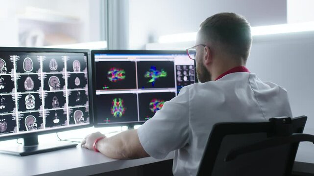 Medical hospital: neurologist use computer, analyze patient's MRI, diagnose brain. Health Clinic Lab: A professional doctor examines a functioning CT scan