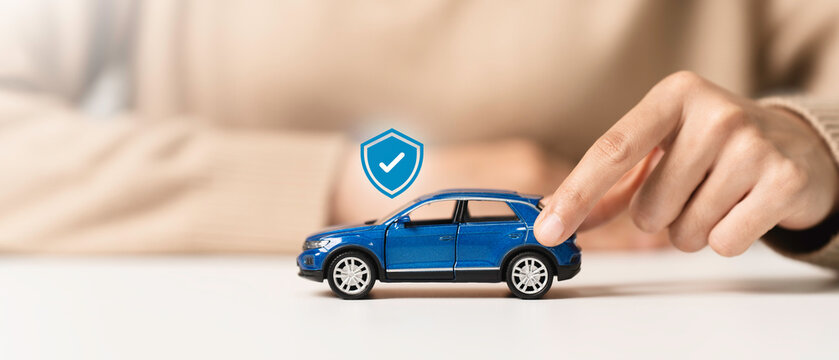 Car insurance, vehicle protection concept. Woman hand holding blue toy car with car insurance icon to coverage covered automobile for financial security.